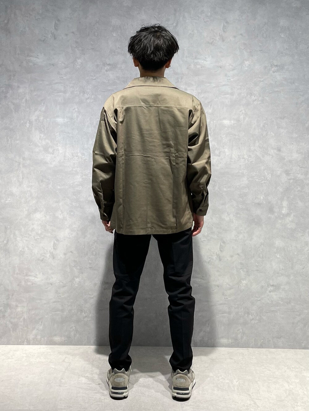 グリーン系のブルゾン、ホワイト系のTシャツ/カットソー、ブラック系のスラックスを着用したメンズの春コーディネートの3枚目の写真