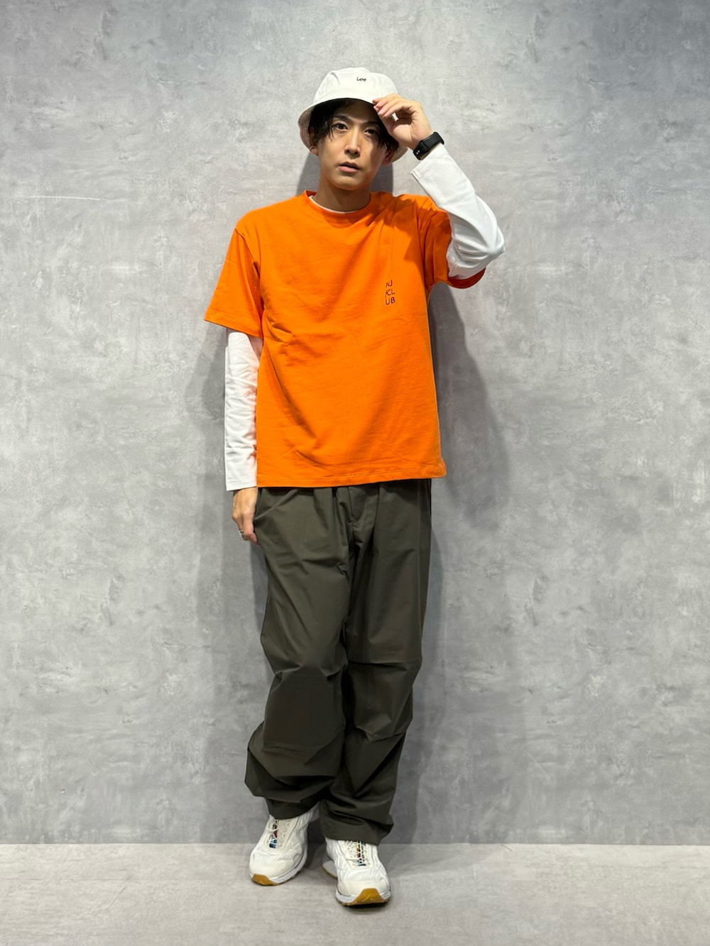 オレンジ系のTシャツ/カットソー、グリーン系のその他パンツ、ホワイト系のTシャツ/カットソーを着用したメンズの夏コーディネートの2枚目の写真
