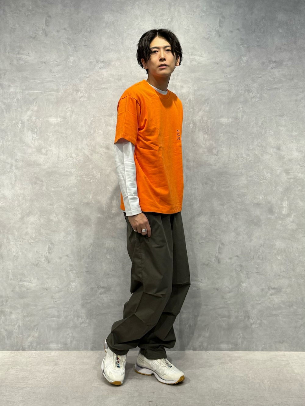 オレンジ系のTシャツ/カットソー、グリーン系のその他パンツ、ホワイト系のTシャツ/カットソーを着用したメンズの夏コーディネートの3枚目の写真