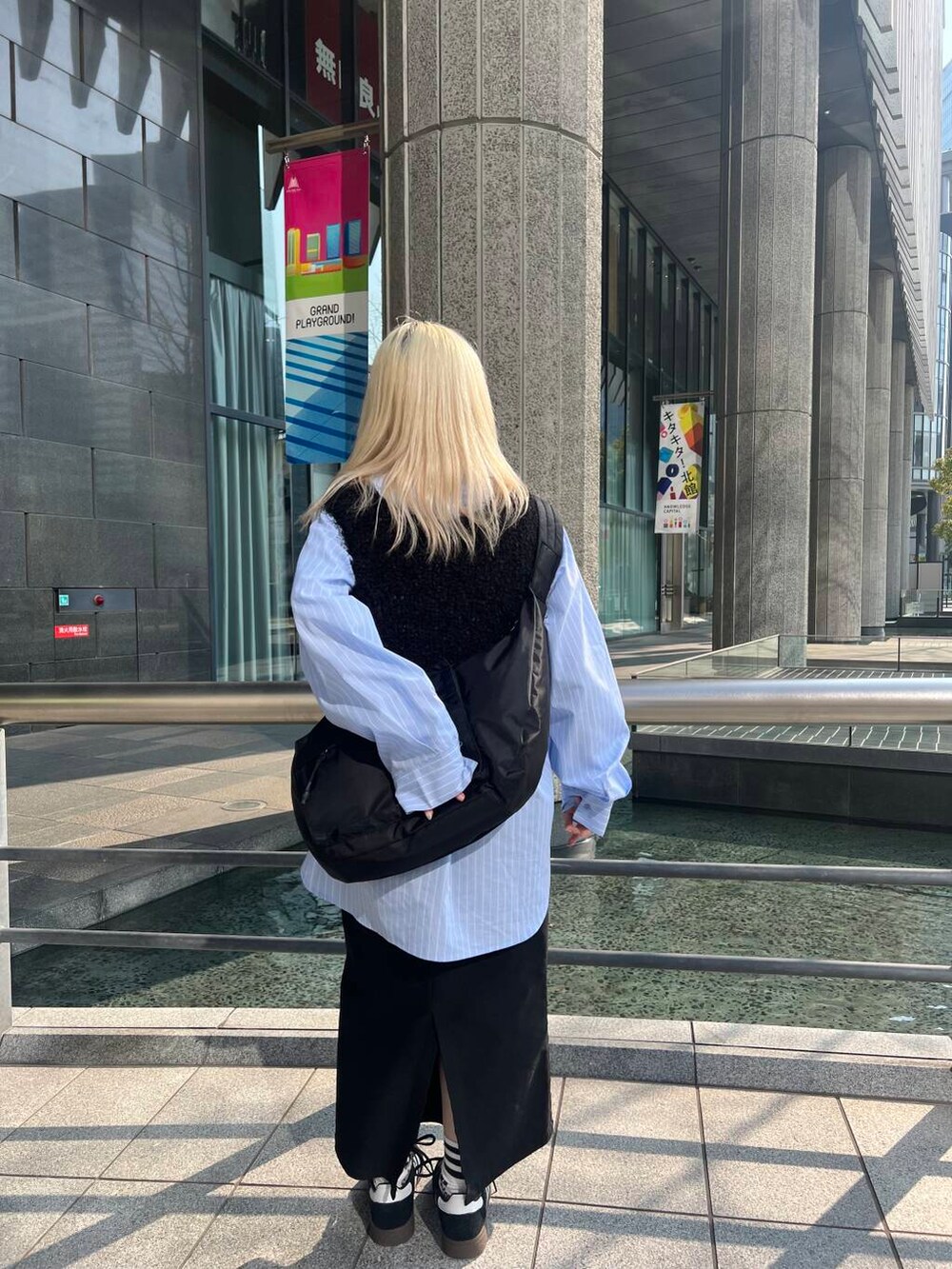 ブラック系のショルダーバッグ、ブラック系のスカート、ブルー系のシャツ/ブラウスを着用したレディースの冬コーディネートの3枚目の写真