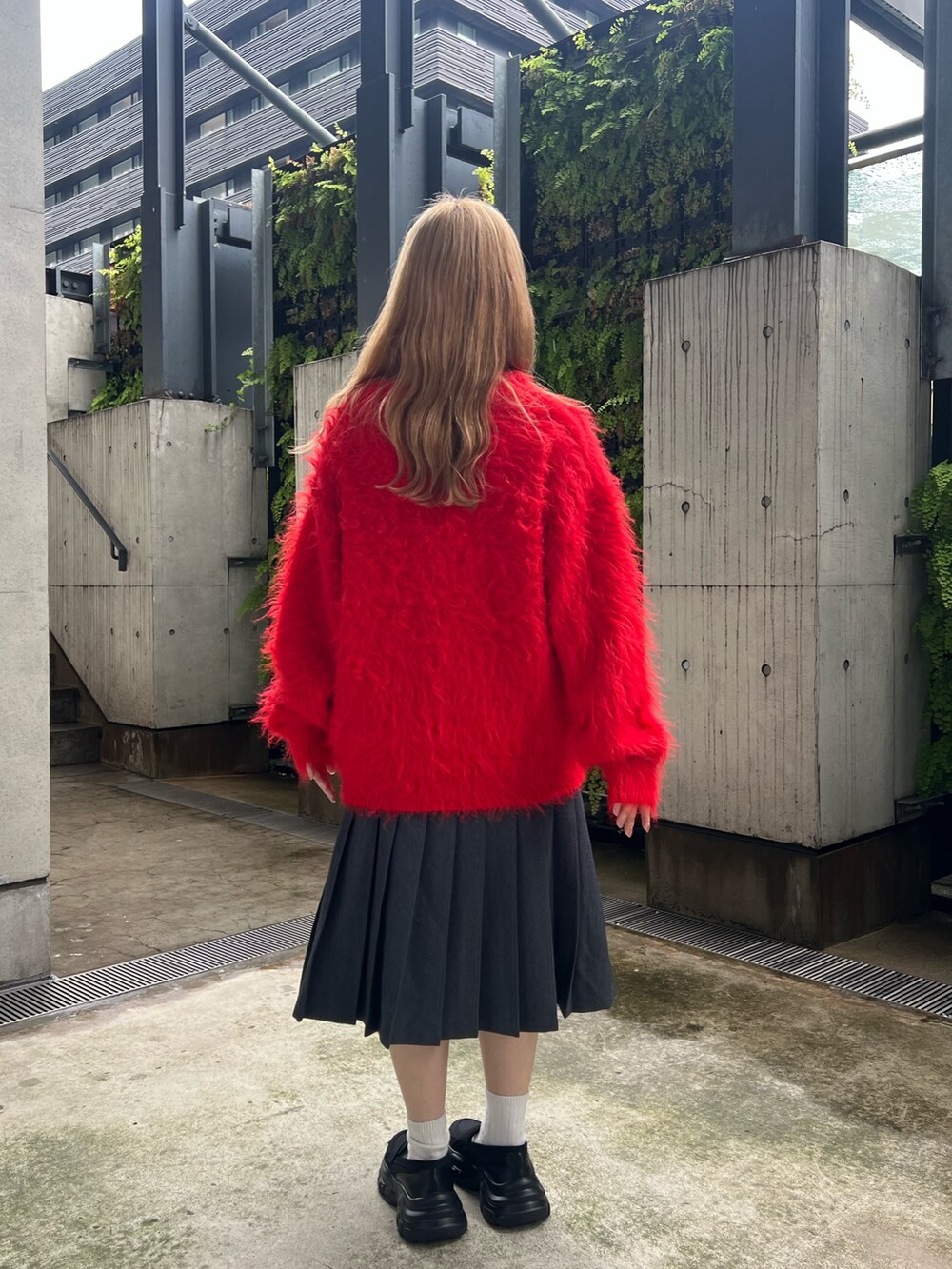 レッド系のニット/セーター、グリーン系のスカート、ブラック系のローファーを着用したレディースの秋コーディネートの2枚目の写真