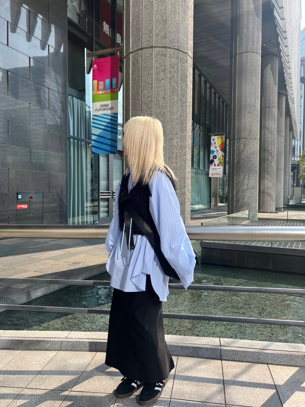 ブラック系のショルダーバッグ、ブラック系のスカート、ブルー系のシャツ/ブラウスを着用したレディースの冬コーディネートの2枚目の写真