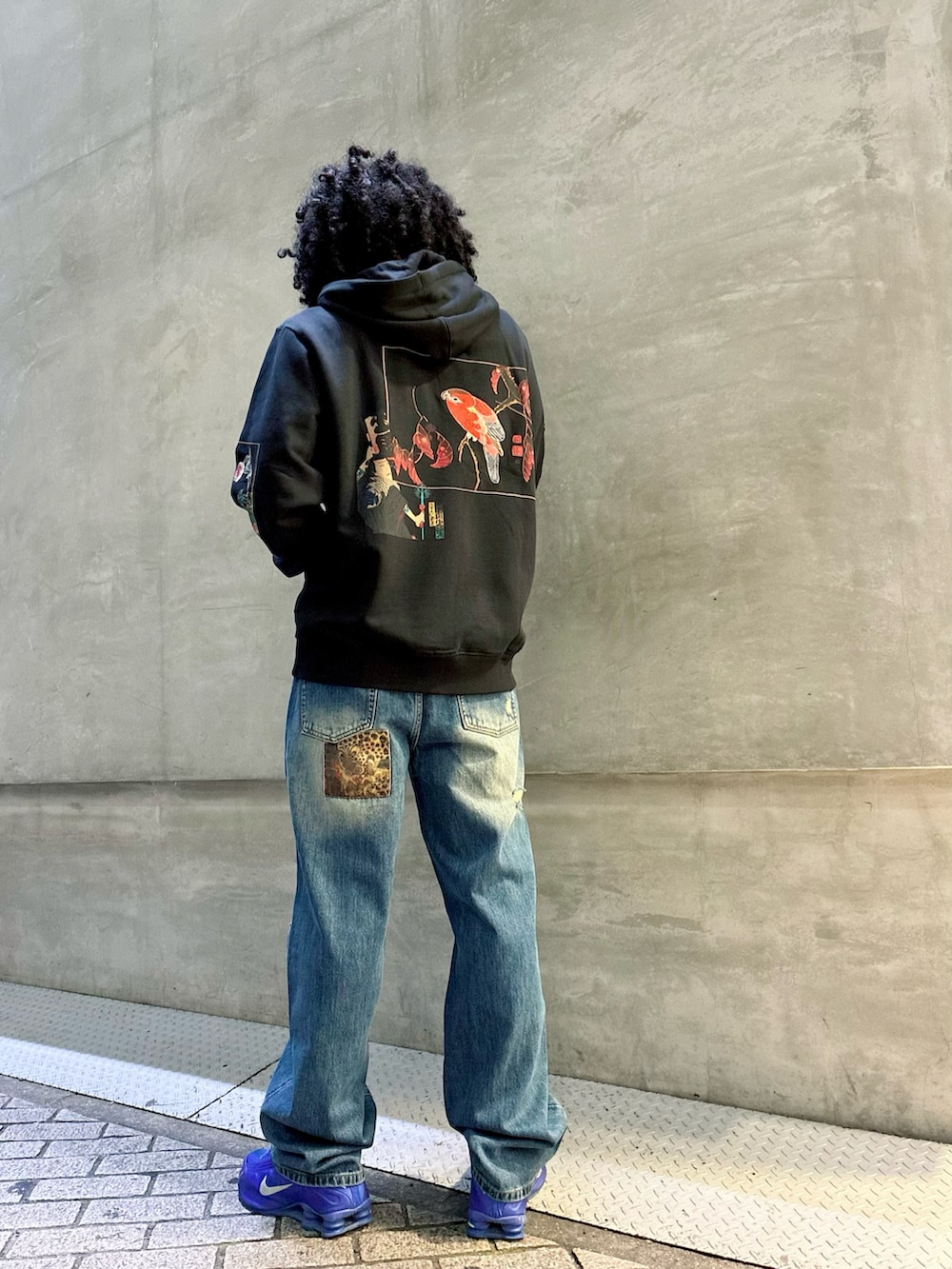 ブラック系のスウェット、ブルー系のデニムパンツ、ブルー系のスニーカーを着用したメンズの秋コーディネートの2枚目の写真