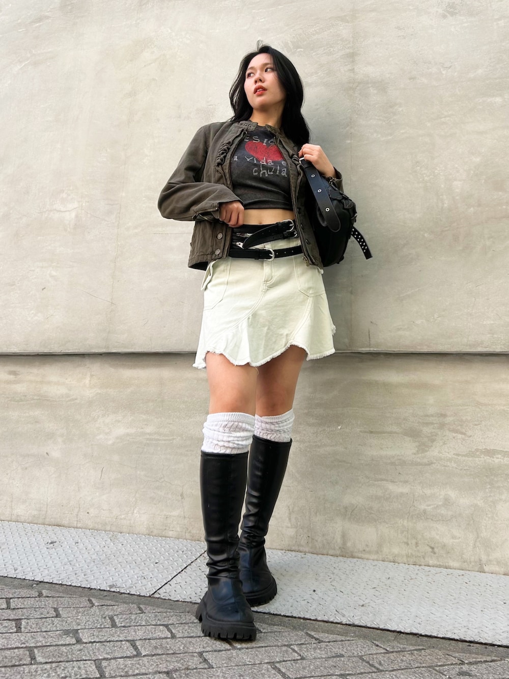 グリーン系のブルゾン、ホワイト系のスカート、ブラウン系のハンドバッグを着用したレディースの春コーディネートの2枚目の写真