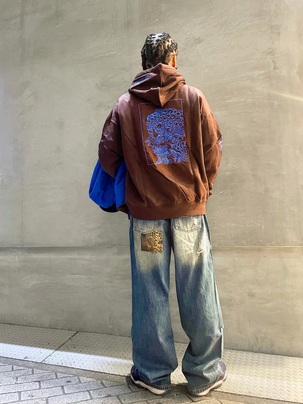 ブルー系のブルゾン、ブルー系のデニムパンツ、ブラウン系のパーカーを着用したメンズの秋コーディネートの3枚目の写真