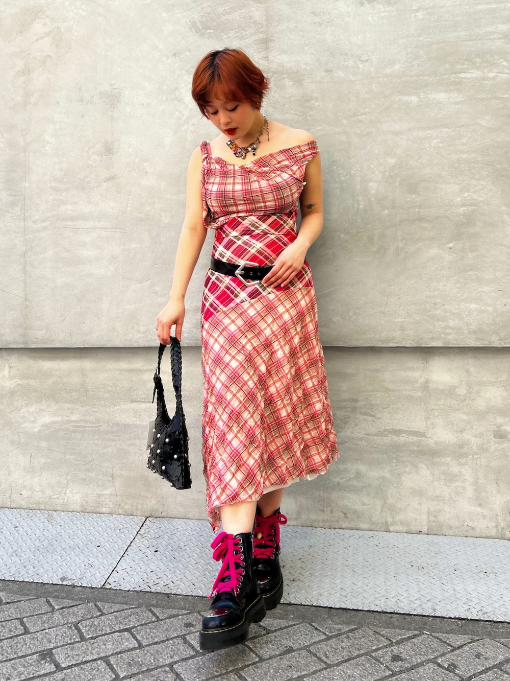 レッド系のワンピース、ブラック系のショルダーバッグ、ブラック系のブーツを着用したレディースの春コーディネートの2枚目の写真