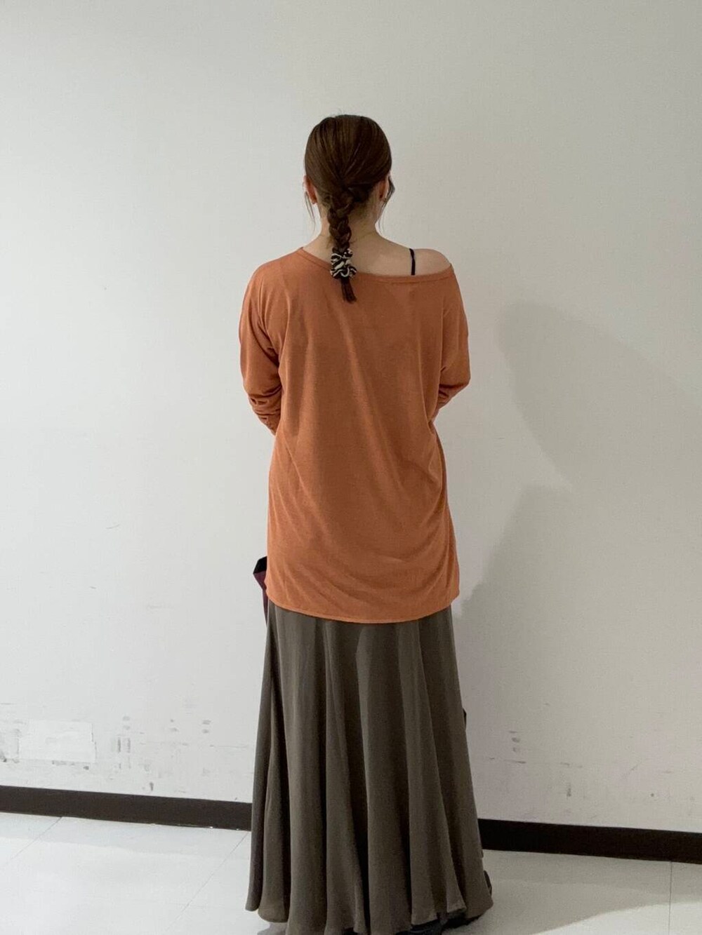 グリーン系のスカート、オレンジ系のTシャツ/カットソー、ブラック系のスニーカーを着用したレディースの夏コーディネートの3枚目の写真