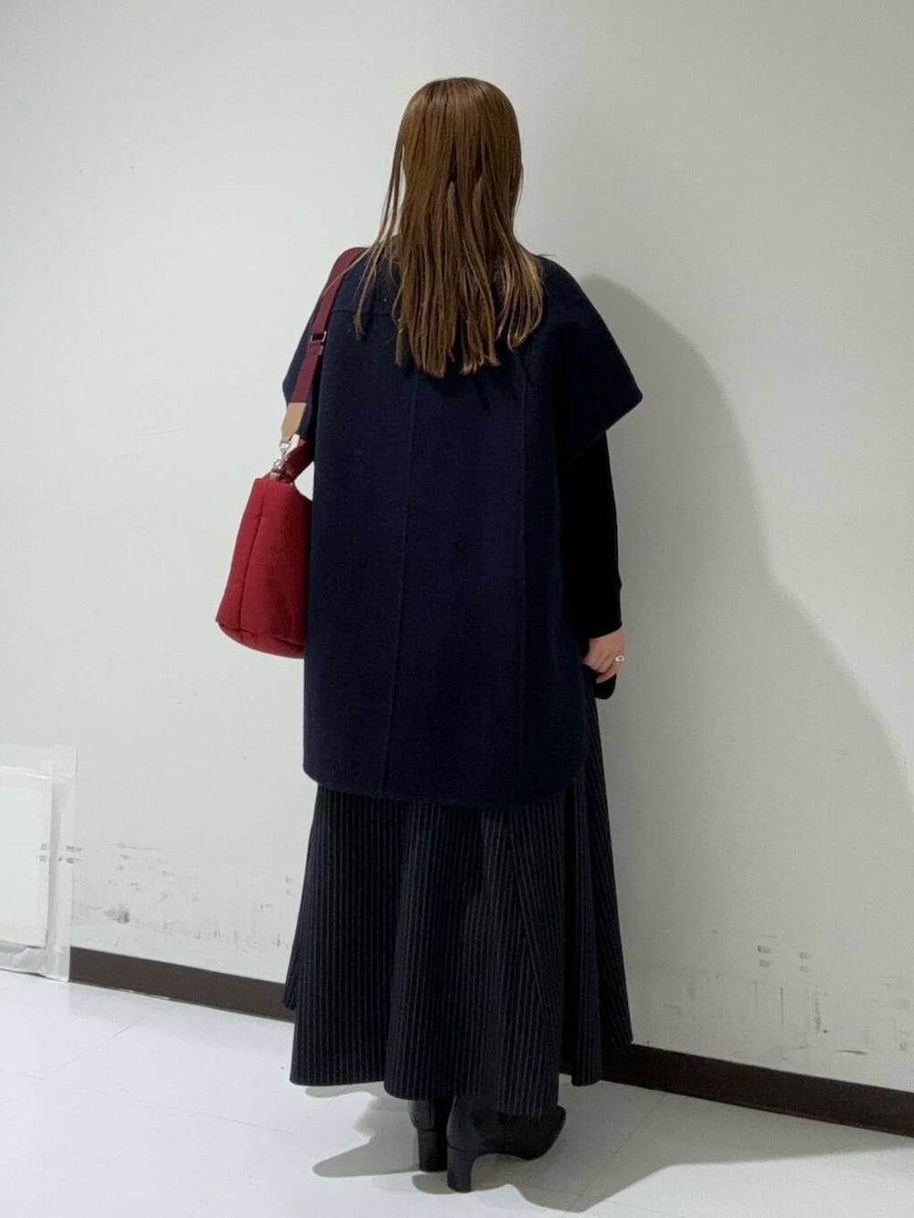 ブルー系のスカート、ブラック系のカーディガン/ボレロ、ブルー系のポンチョを着用したレディースの秋コーディネートの3枚目の写真