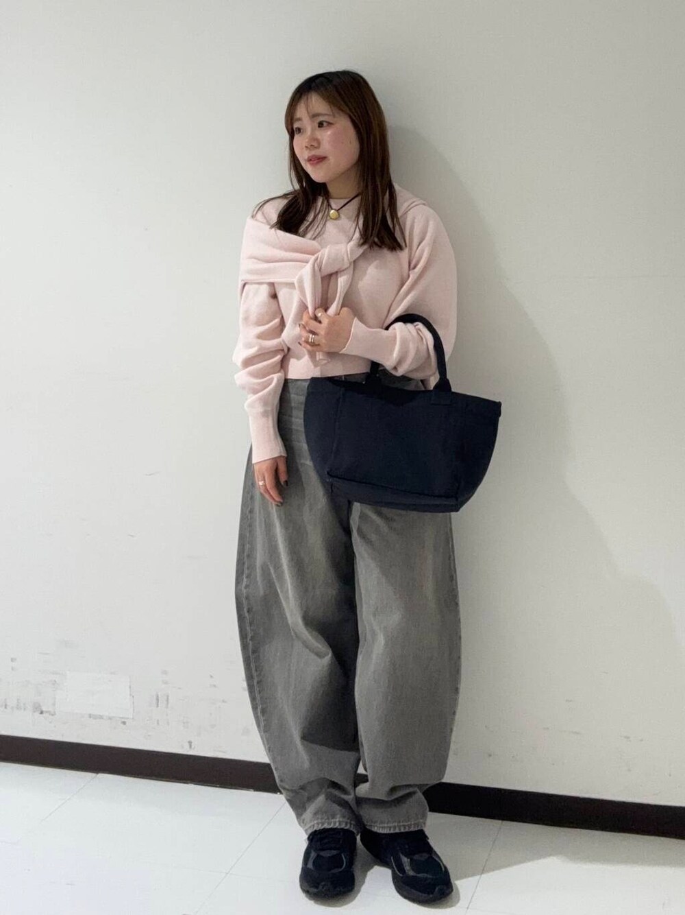 グリーン系のデニムパンツ、ベージュ系のトレンチコート、ブラック系のショルダーバッグを着用したレディースの冬コーディネートの3枚目の写真