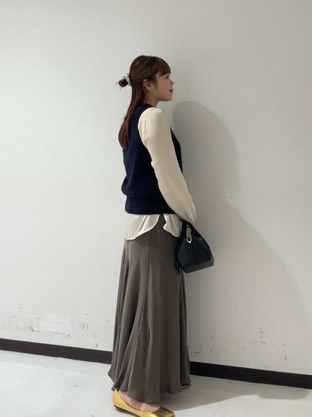 グリーン系のスカート、ホワイト系のシャツ/ブラウス、ブルー系のベストを着用したレディースの秋コーディネートの3枚目の写真