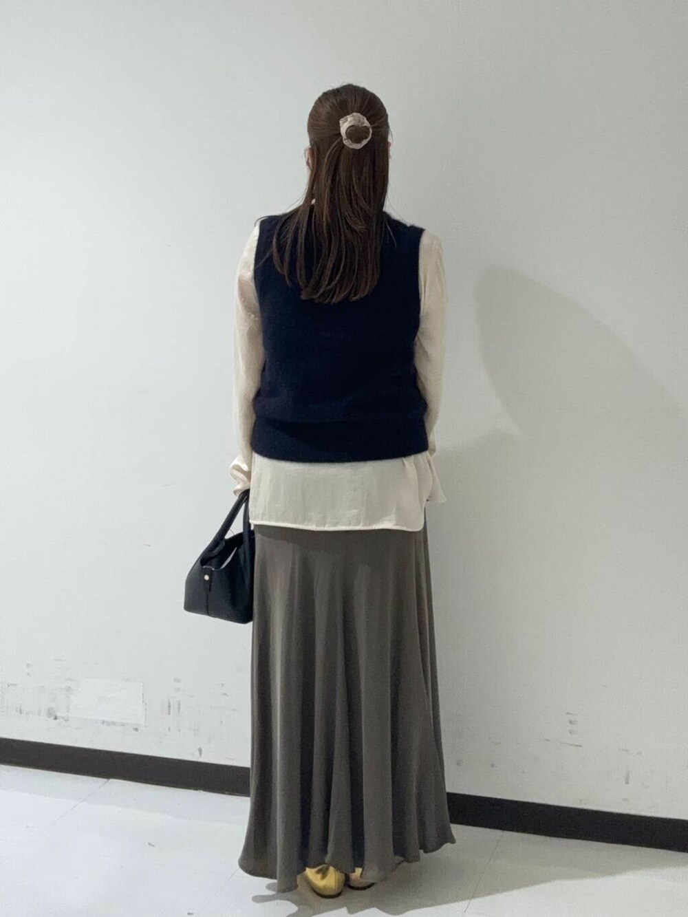 グリーン系のスカート、ホワイト系のシャツ/ブラウス、ブルー系のベストを着用したレディースの秋コーディネートの4枚目の写真