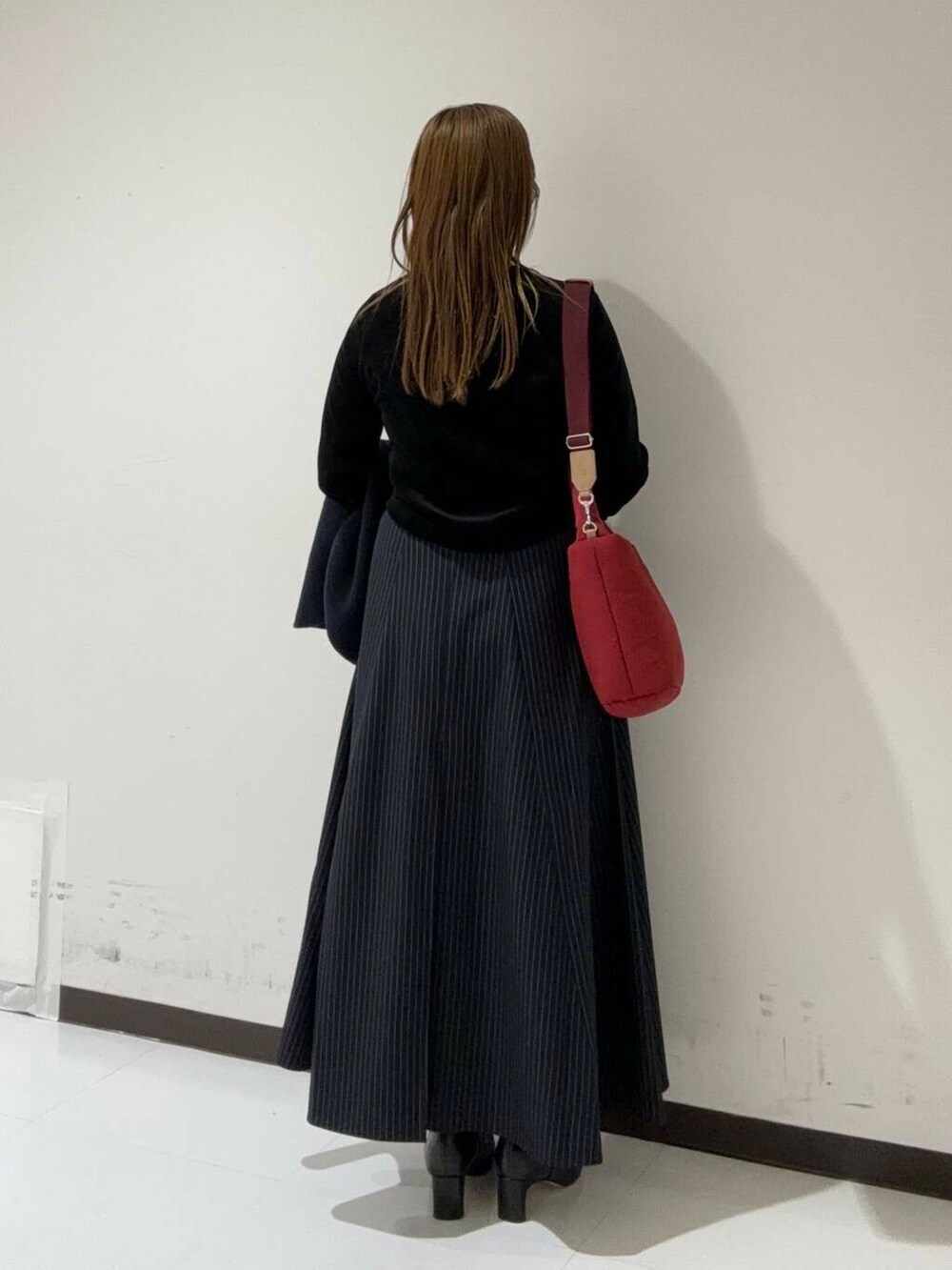 ブルー系のスカート、ブラック系のカーディガン/ボレロ、ブラック系のブーツを着用したレディースの秋コーディネートの3枚目の写真