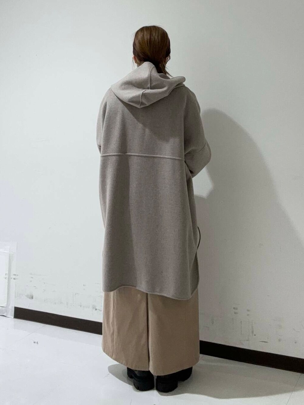 ブラック系のブーツ、ベージュ系のその他アウター、ブラック系のTシャツ/カットソーを着用したレディースの秋コーディネートの3枚目の写真