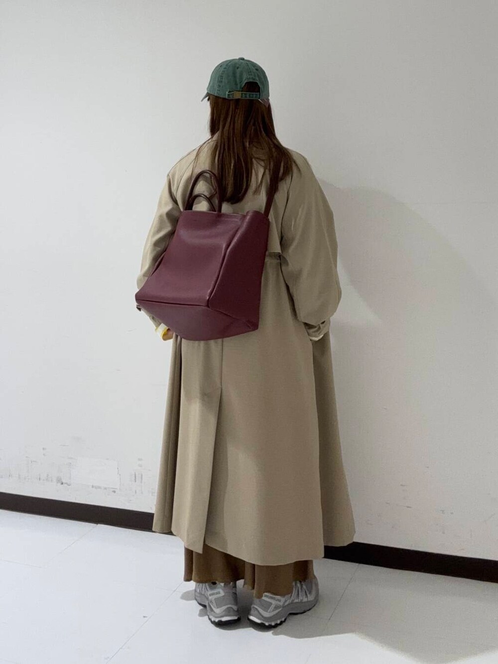 イエロー系のスカート、ベージュ系のトレンチコート、イエロー系のTシャツ/カットソーを着用したレディースの冬コーディネートの3枚目の写真