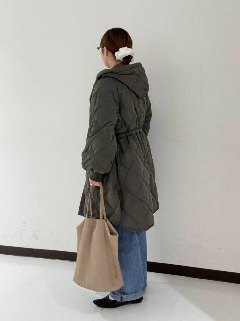 ブルー系のデニムパンツ、グレー系のダウンジャケット/コート、オレンジ系のシャツ/ブラウスを着用したレディースの冬コーディネートの2枚目の写真