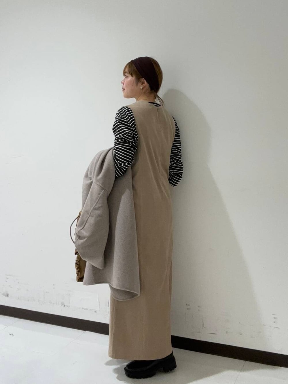 ブラック系のブーツ、ベージュ系のその他アウター、ブラック系のTシャツ/カットソーを着用したレディースの秋コーディネートの2枚目の写真