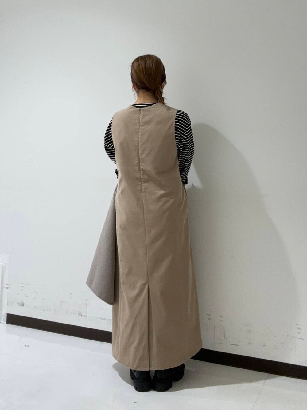 ブラック系のブーツ、ベージュ系のその他アウター、ブラック系のTシャツ/カットソーを着用したレディースの秋コーディネートの3枚目の写真