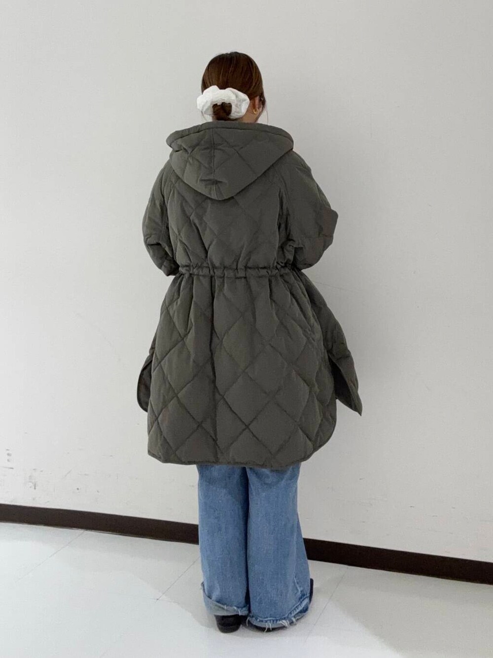 ブルー系のデニムパンツ、グレー系のダウンジャケット/コート、オレンジ系のシャツ/ブラウスを着用したレディースの冬コーディネートの3枚目の写真