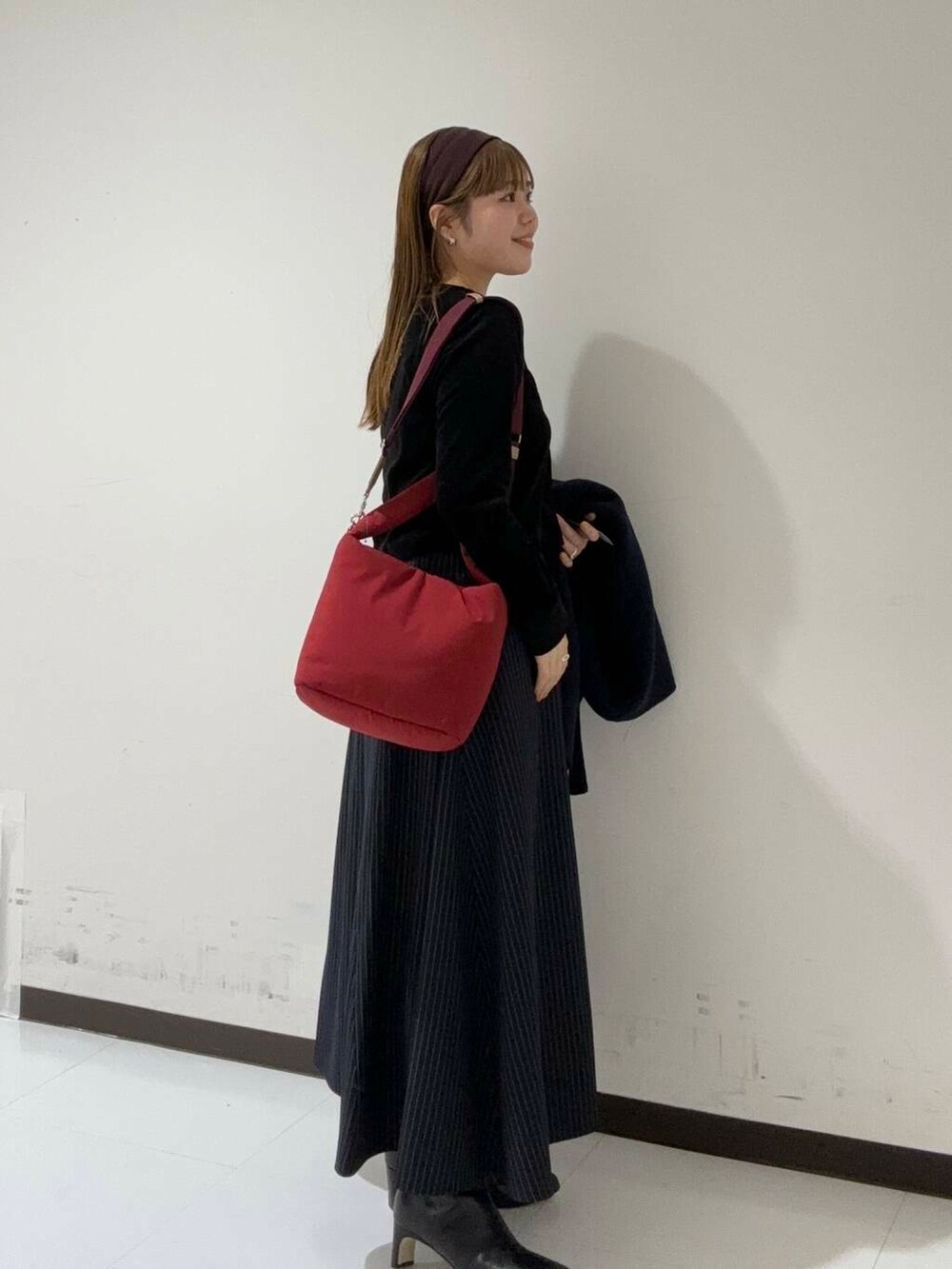 ブルー系のスカート、ブラック系のカーディガン/ボレロ、ブラック系のブーツを着用したレディースの秋コーディネートの2枚目の写真