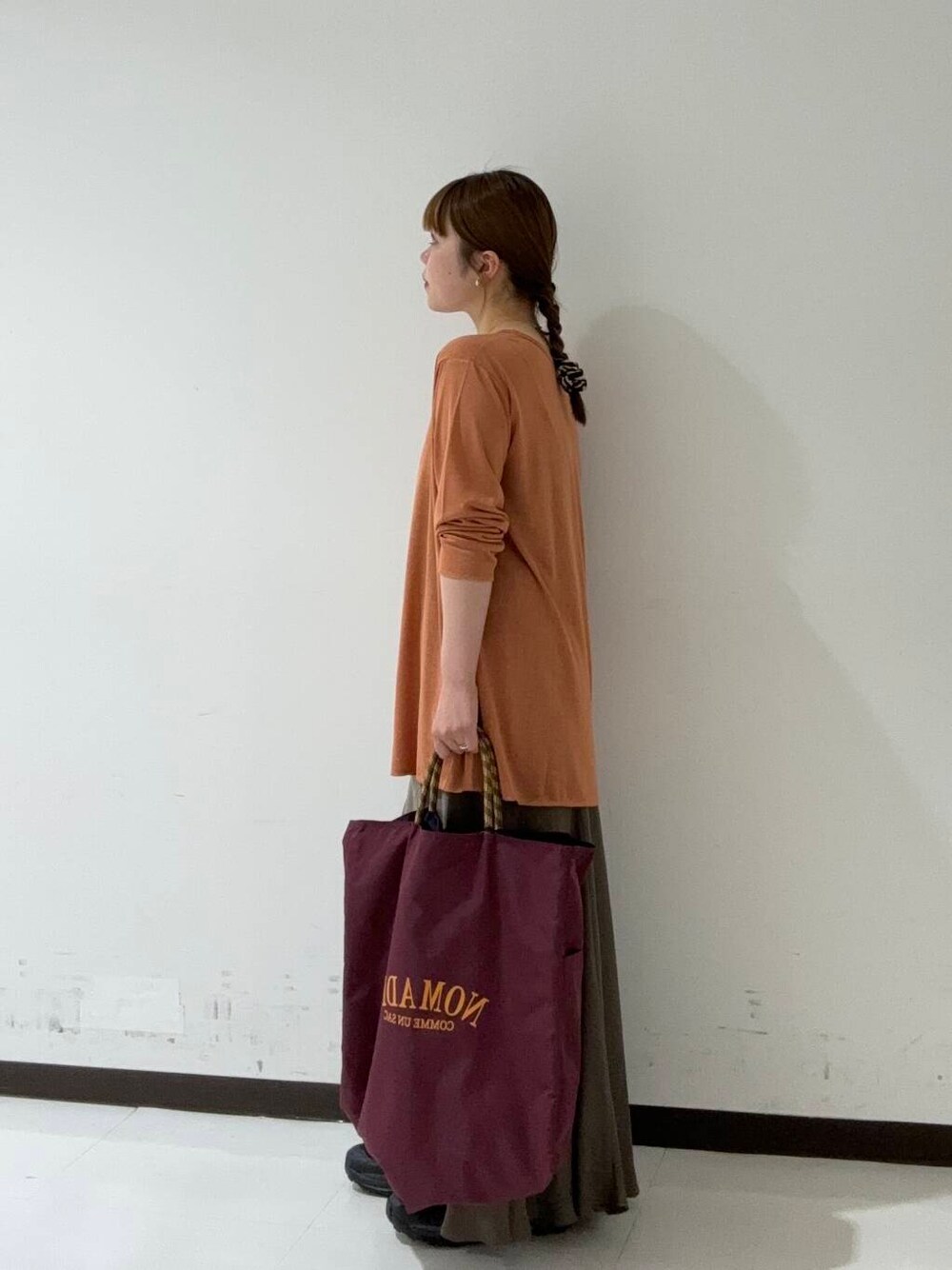 グリーン系のスカート、オレンジ系のTシャツ/カットソー、ブラック系のスニーカーを着用したレディースの夏コーディネートの2枚目の写真