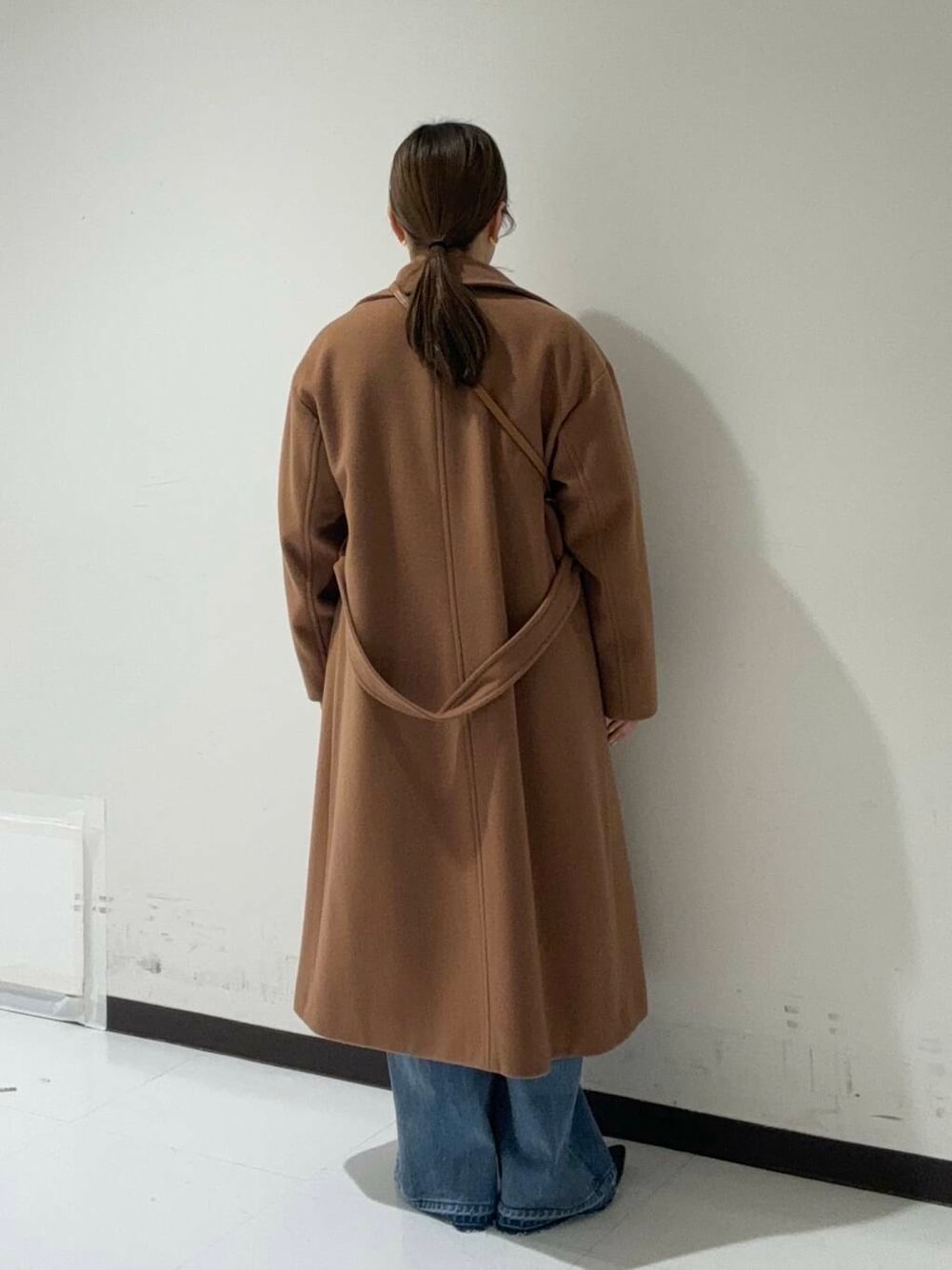 イエロー系のチェスターコート、ブルー系のデニムパンツ、レッド系のニット/セーターを着用したレディースの冬コーディネートの3枚目の写真