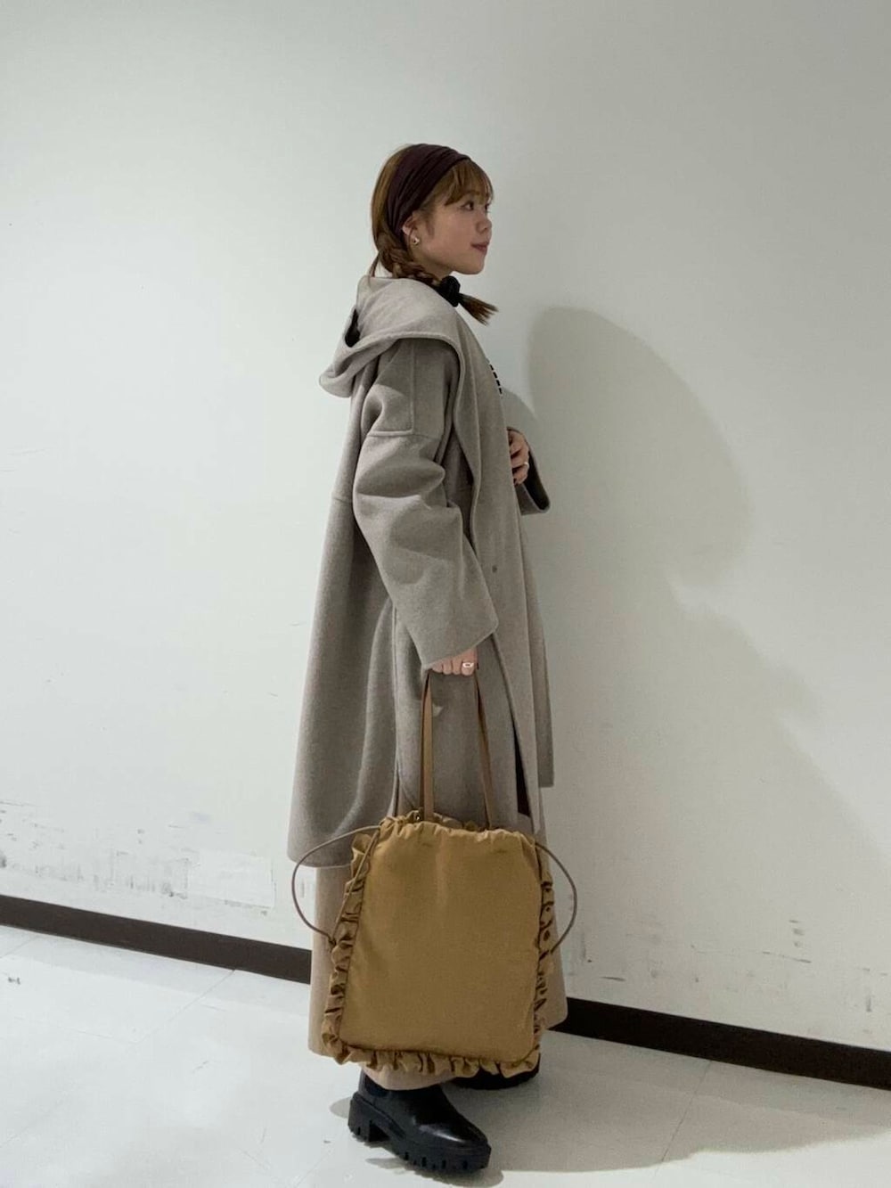 ブラック系のブーツ、ベージュ系のその他アウター、ブラック系のTシャツ/カットソーを着用したレディースの秋コーディネートの2枚目の写真