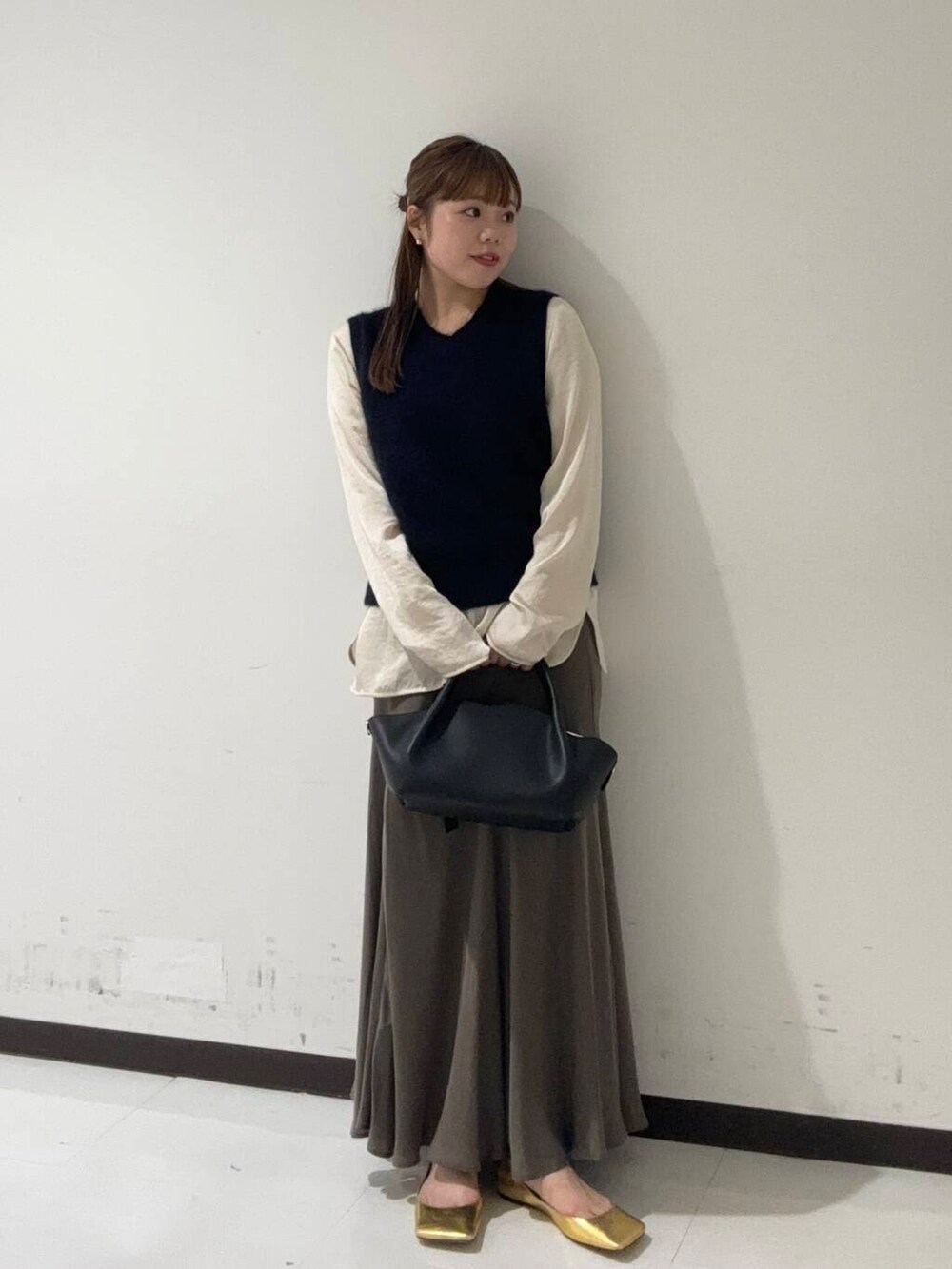 グリーン系のスカート、ホワイト系のシャツ/ブラウス、ブルー系のベストを着用したレディースの秋コーディネートの2枚目の写真