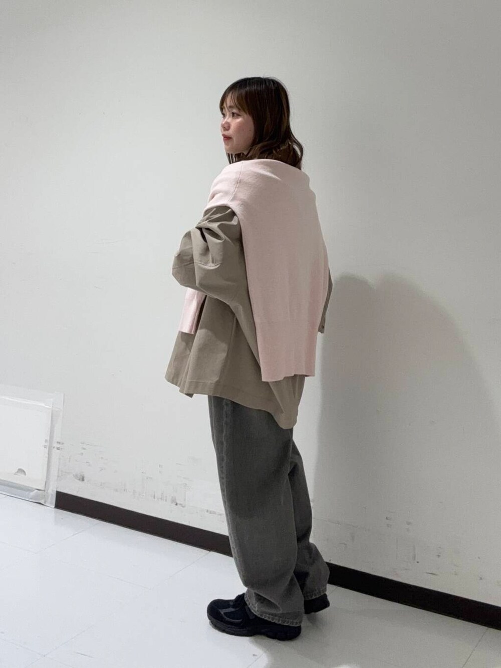 グリーン系のデニムパンツ、ベージュ系のトレンチコート、ブラック系のショルダーバッグを着用したレディースの冬コーディネートの2枚目の写真