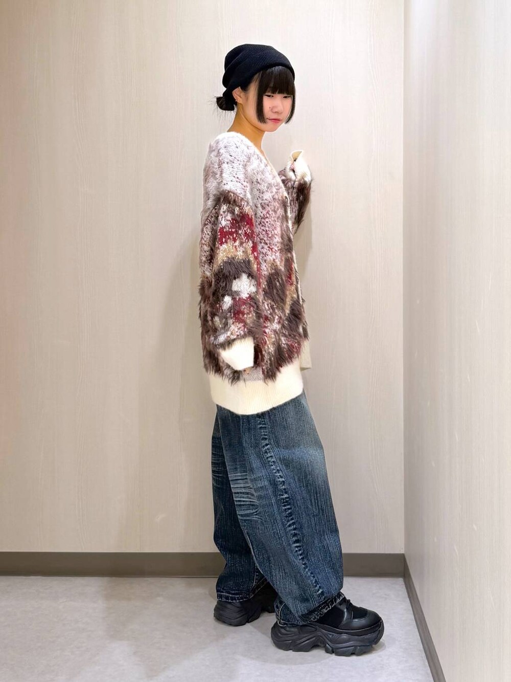 ブラック系のブーツ、ホワイト系のカーディガン/ボレロ、ブルー系のデニムパンツを着用したレディースの秋コーディネートの4枚目の写真