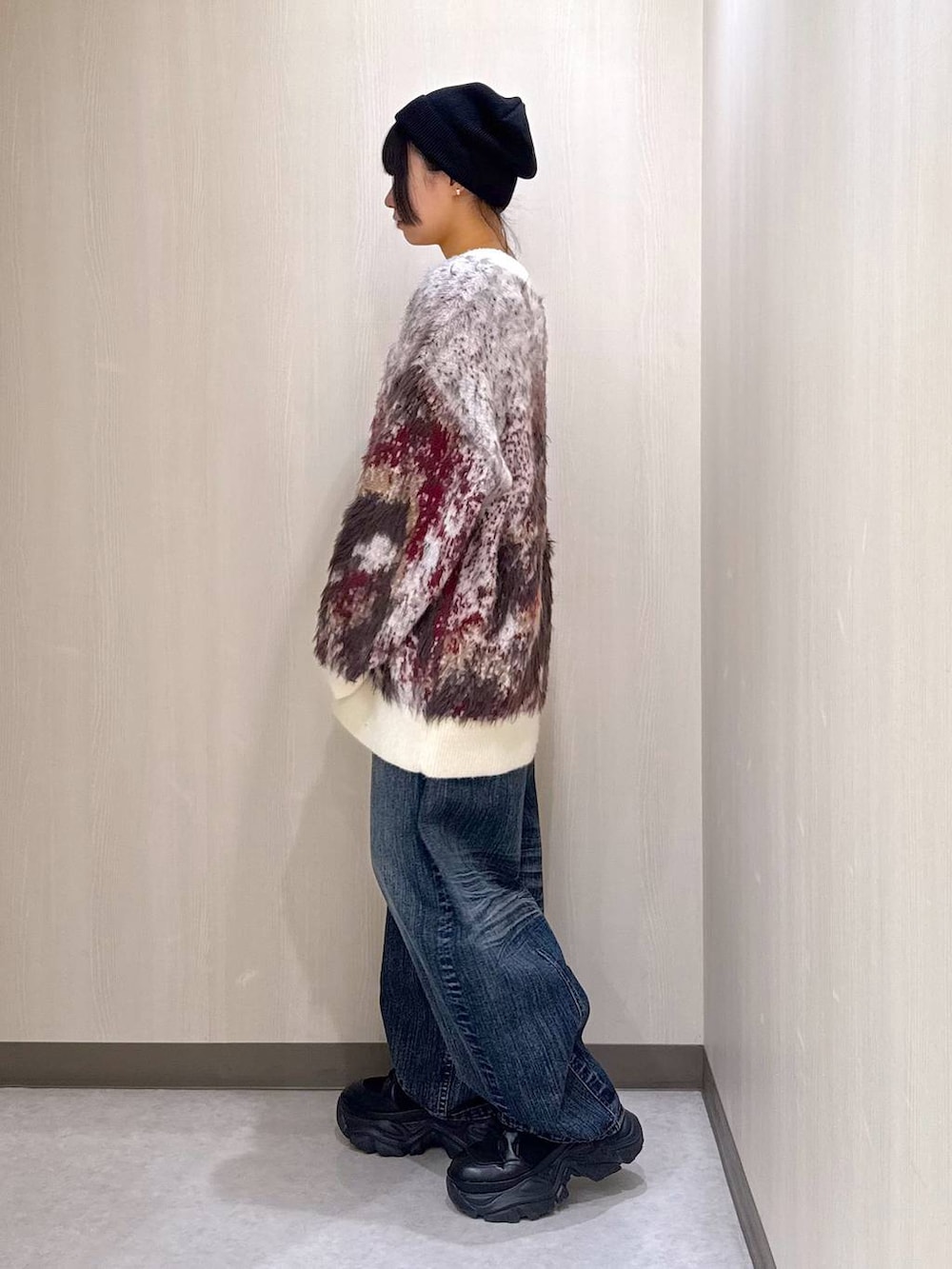 ブラック系のブーツ、ホワイト系のカーディガン/ボレロ、ブルー系のデニムパンツを着用したレディースの秋コーディネートの2枚目の写真