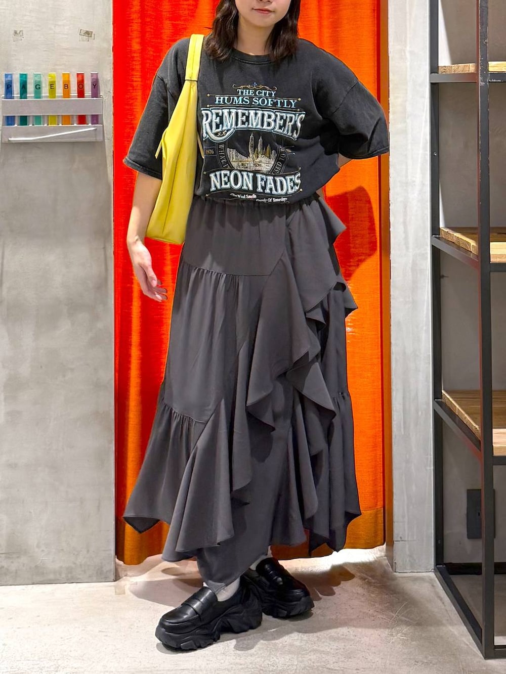 グレー系のスカート、イエロー系のトートバッグ、グレー系のTシャツ/カットソーを着用したレディースの春コーディネートの2枚目の写真