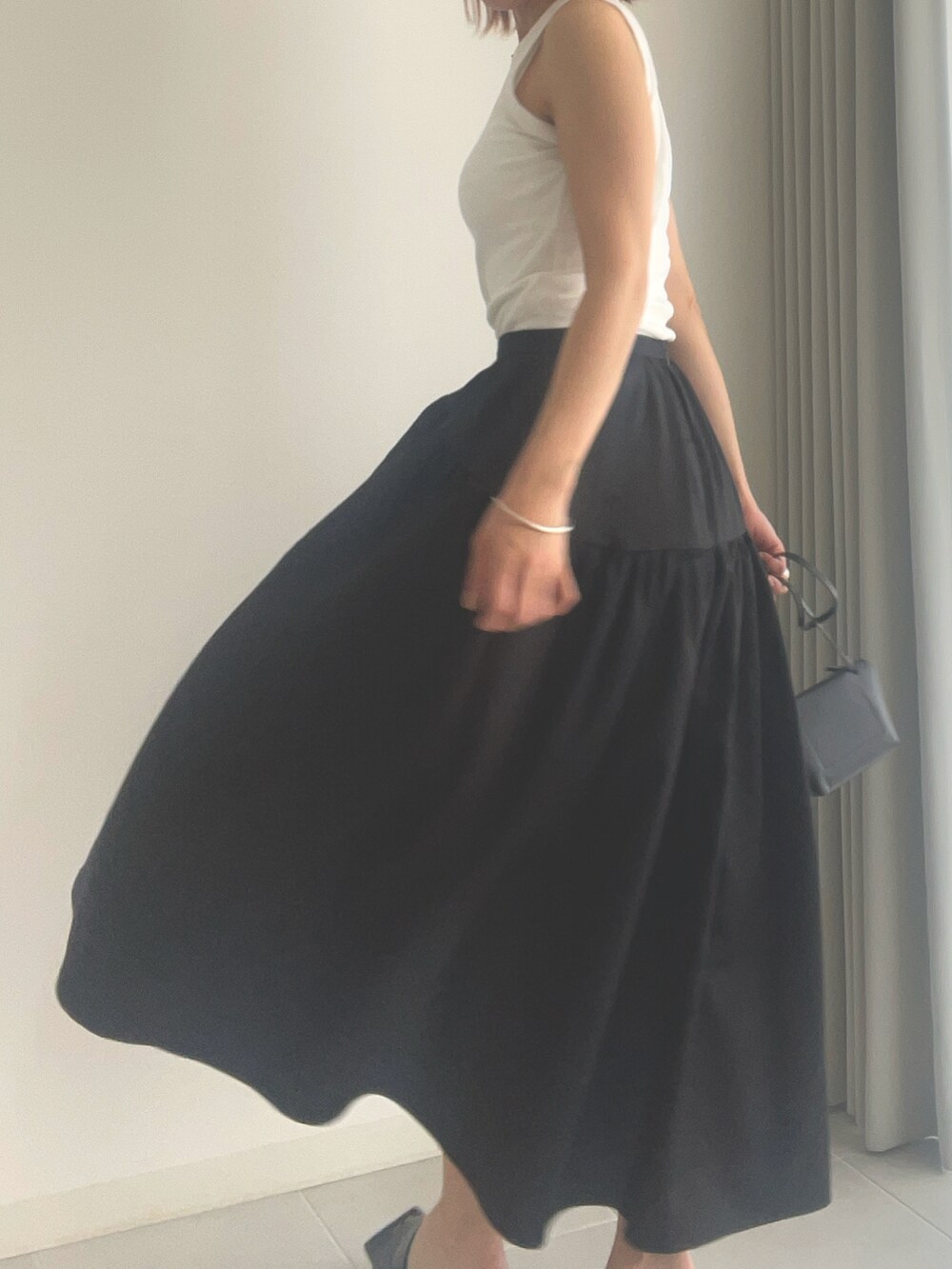 ブラック系のサンダル、ブラック系のスカート、ホワイト系のタンクトップを着用したレディースの春コーディネートの3枚目の写真