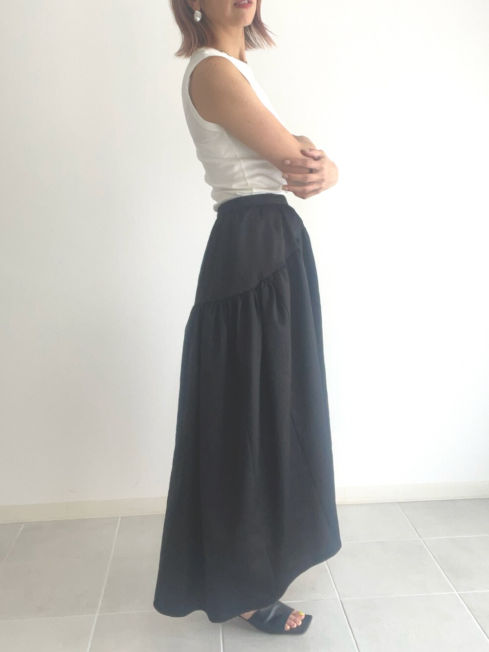 ブラック系のサンダル、ブラック系のスカート、ホワイト系のタンクトップを着用したレディースの春コーディネートの2枚目の写真