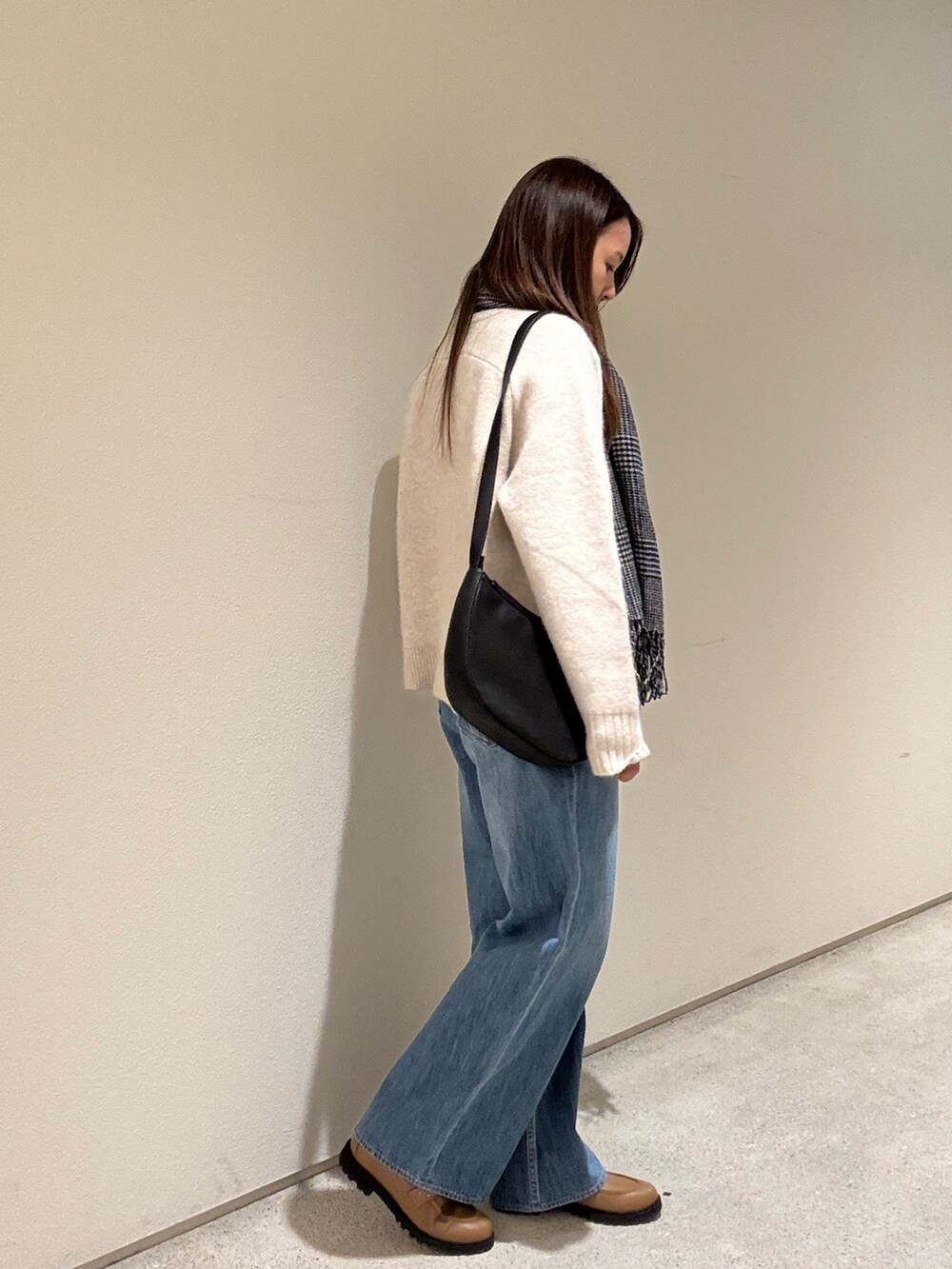 ベージュ系のニット/セーター、ブラック系のショルダーバッグ、ブルー系のデニムパンツを着用したレディースの冬コーディネートの2枚目の写真