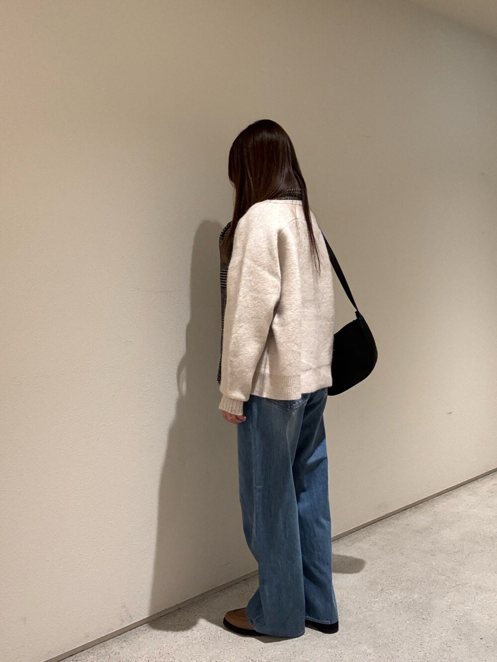 ベージュ系のニット/セーター、ブラック系のショルダーバッグ、ブルー系のデニムパンツを着用したレディースの冬コーディネートの3枚目の写真