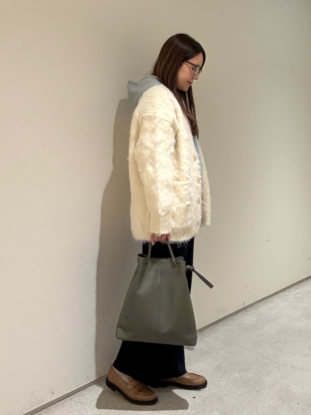 ブルー系のその他パンツ、ベージュ系のカーディガン/ボレロ、グリーン系のトートバッグを着用したレディースの冬コーディネートの2枚目の写真