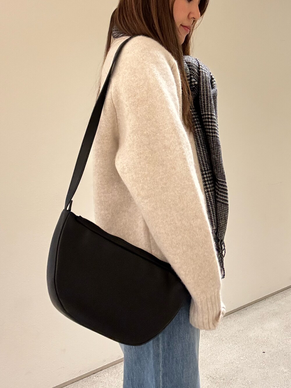 ベージュ系のニット/セーター、ブラック系のショルダーバッグ、ブルー系のデニムパンツを着用したレディースの冬コーディネートの4枚目の写真