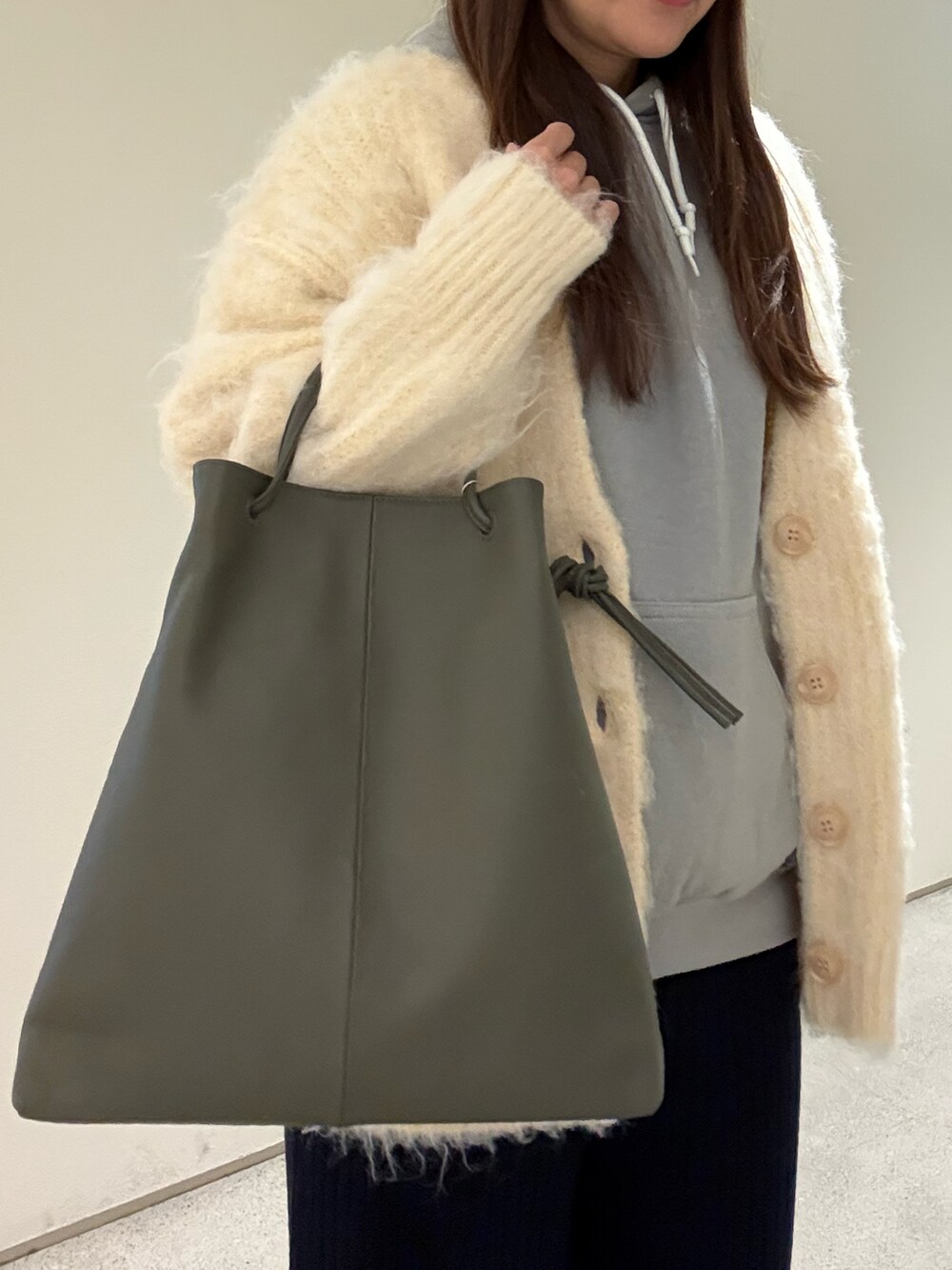 ブルー系のその他パンツ、ベージュ系のカーディガン/ボレロ、グリーン系のトートバッグを着用したレディースの冬コーディネートの3枚目の写真