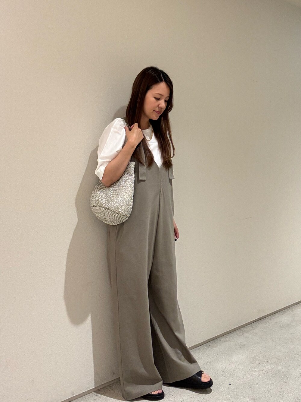 ゴールド系のかごバッグ、ホワイト系のTシャツ/カットソー、グリーン系のサロペット/オーバーオールを着用したレディースの夏コーディネートの3枚目の写真