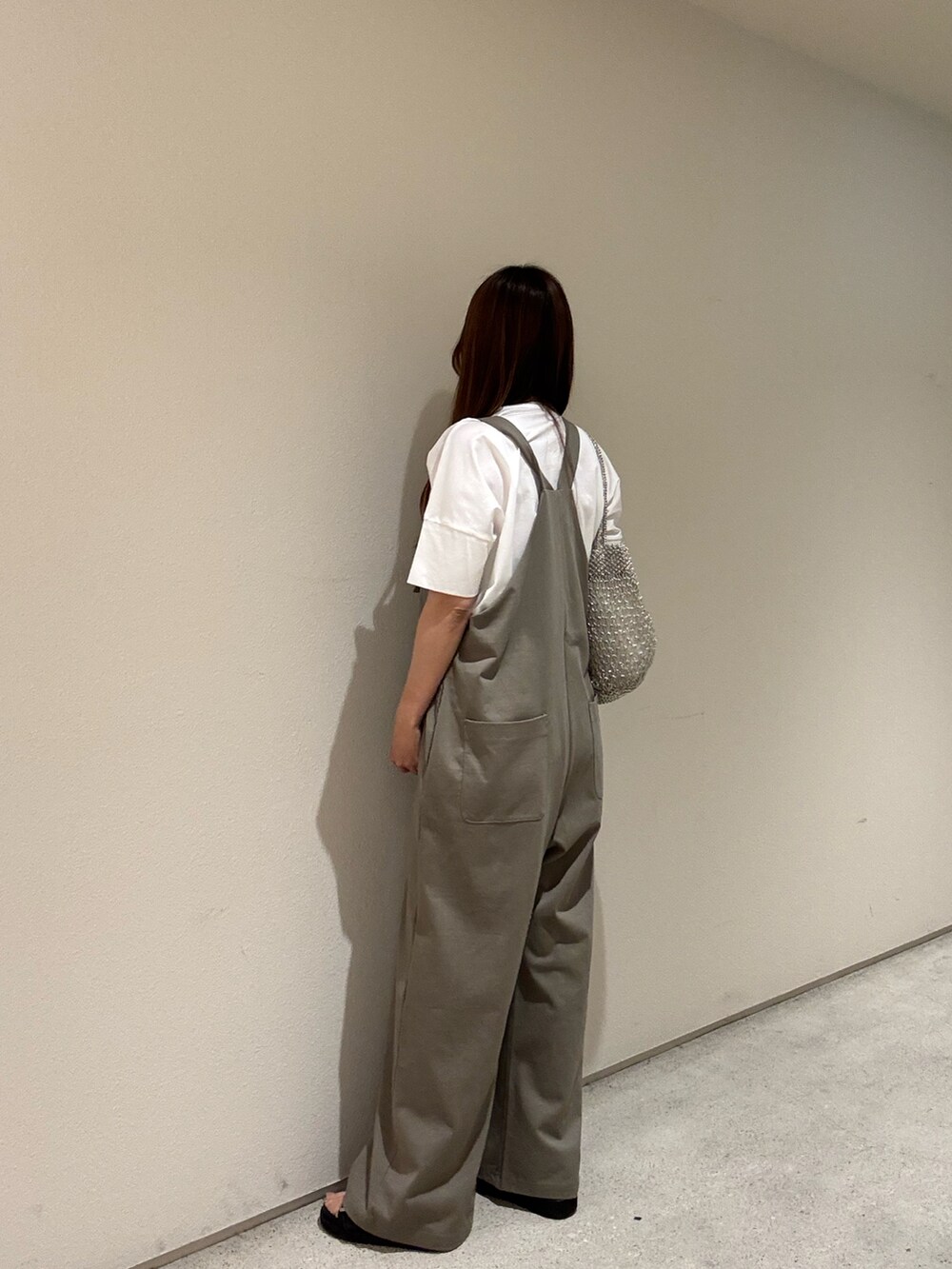 ゴールド系のかごバッグ、ホワイト系のTシャツ/カットソー、グリーン系のサロペット/オーバーオールを着用したレディースの夏コーディネートの2枚目の写真