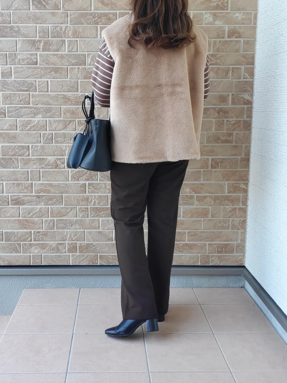 ブラウン系のTシャツ/カットソー、ブラック系のバッグ、ブラウン系のパンツを着用したレディースの秋コーディネートの3枚目の写真