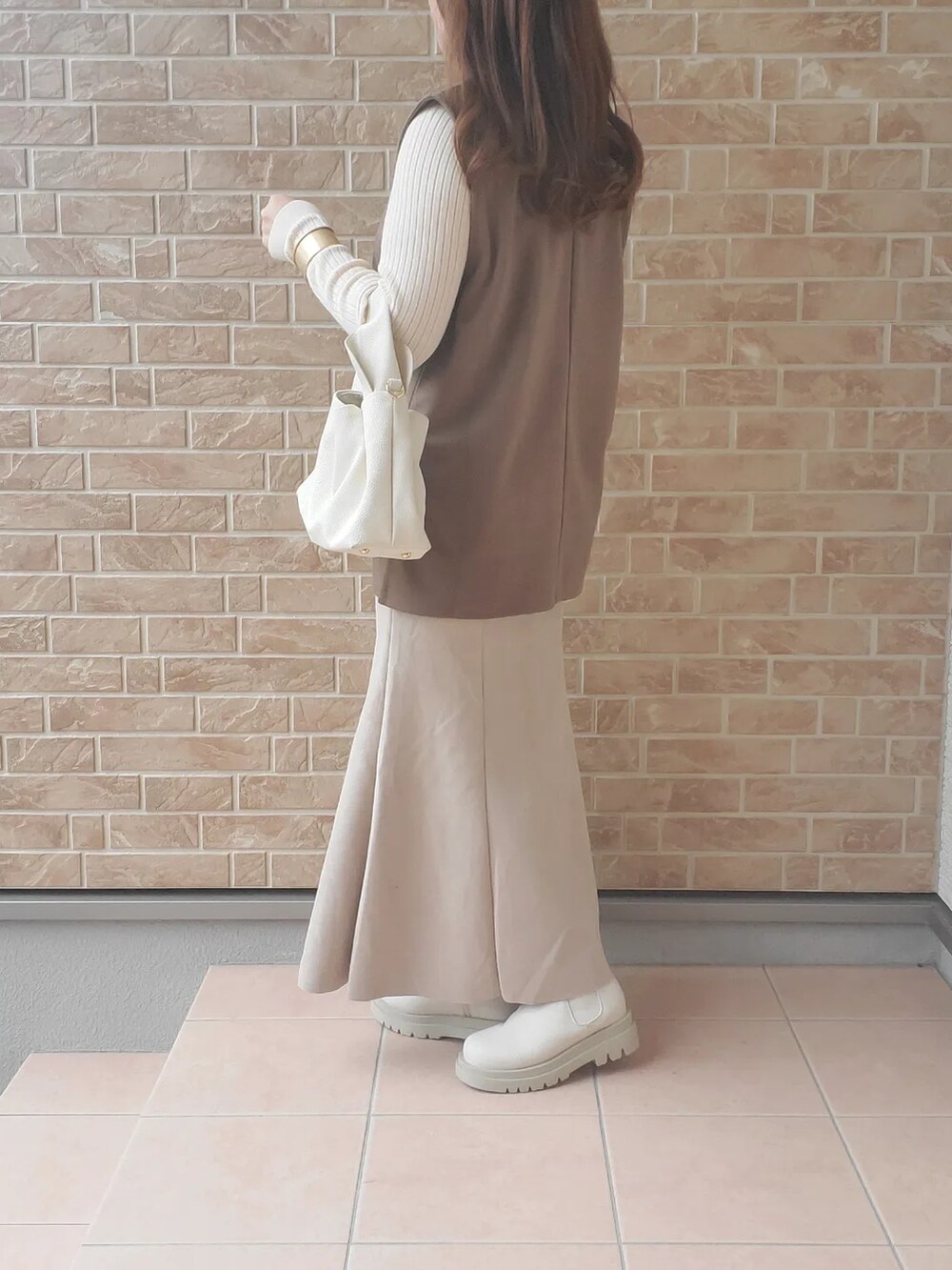ホワイト系のブーツ、ブラウン系のベスト、ホワイト系のバッグを着用したレディースの秋コーディネートの4枚目の写真