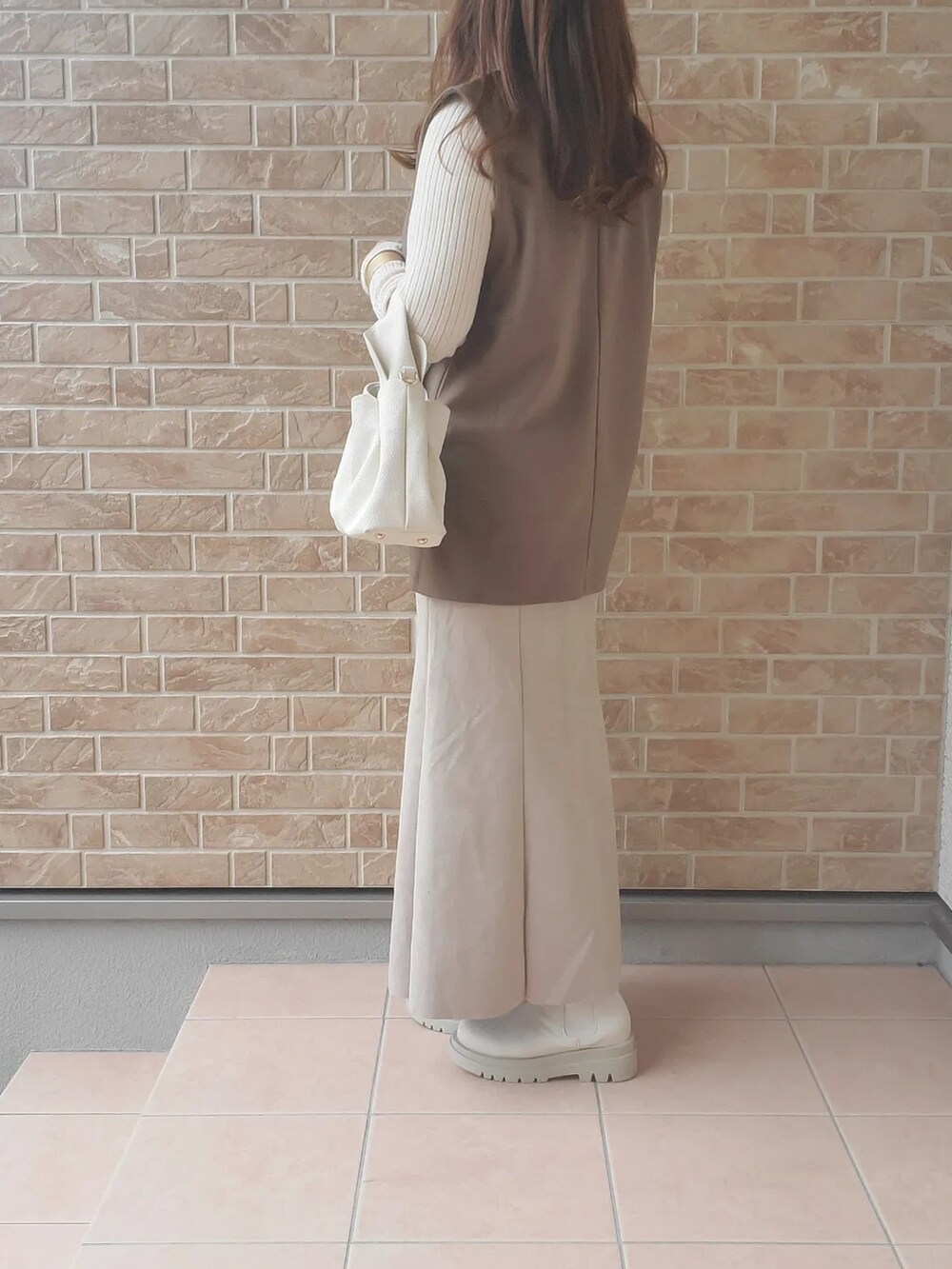 ホワイト系のブーツ、ブラウン系のベスト、ホワイト系のバッグを着用したレディースの秋コーディネートの5枚目の写真