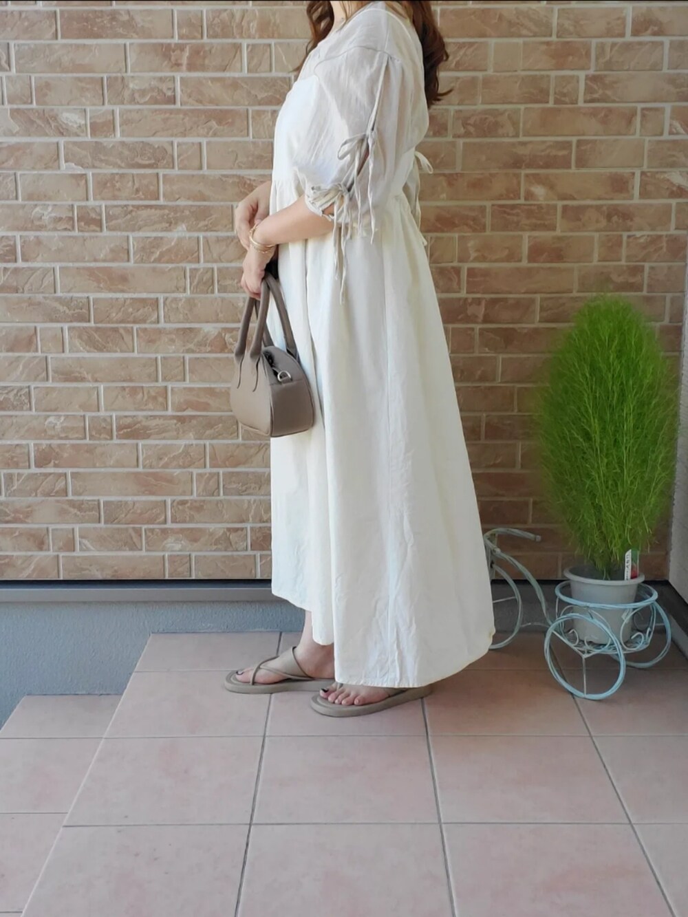 ホワイト系のワンピース、ベージュ系のサンダルを着用したレディースの秋コーディネートの2枚目の写真