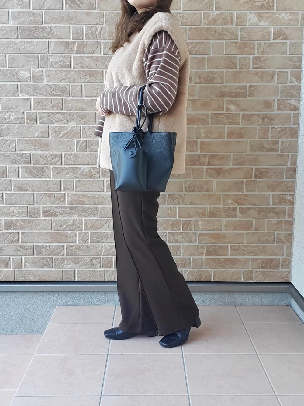 ブラウン系のTシャツ/カットソー、ブラック系のバッグ、ブラウン系のパンツを着用したレディースの秋コーディネートの2枚目の写真