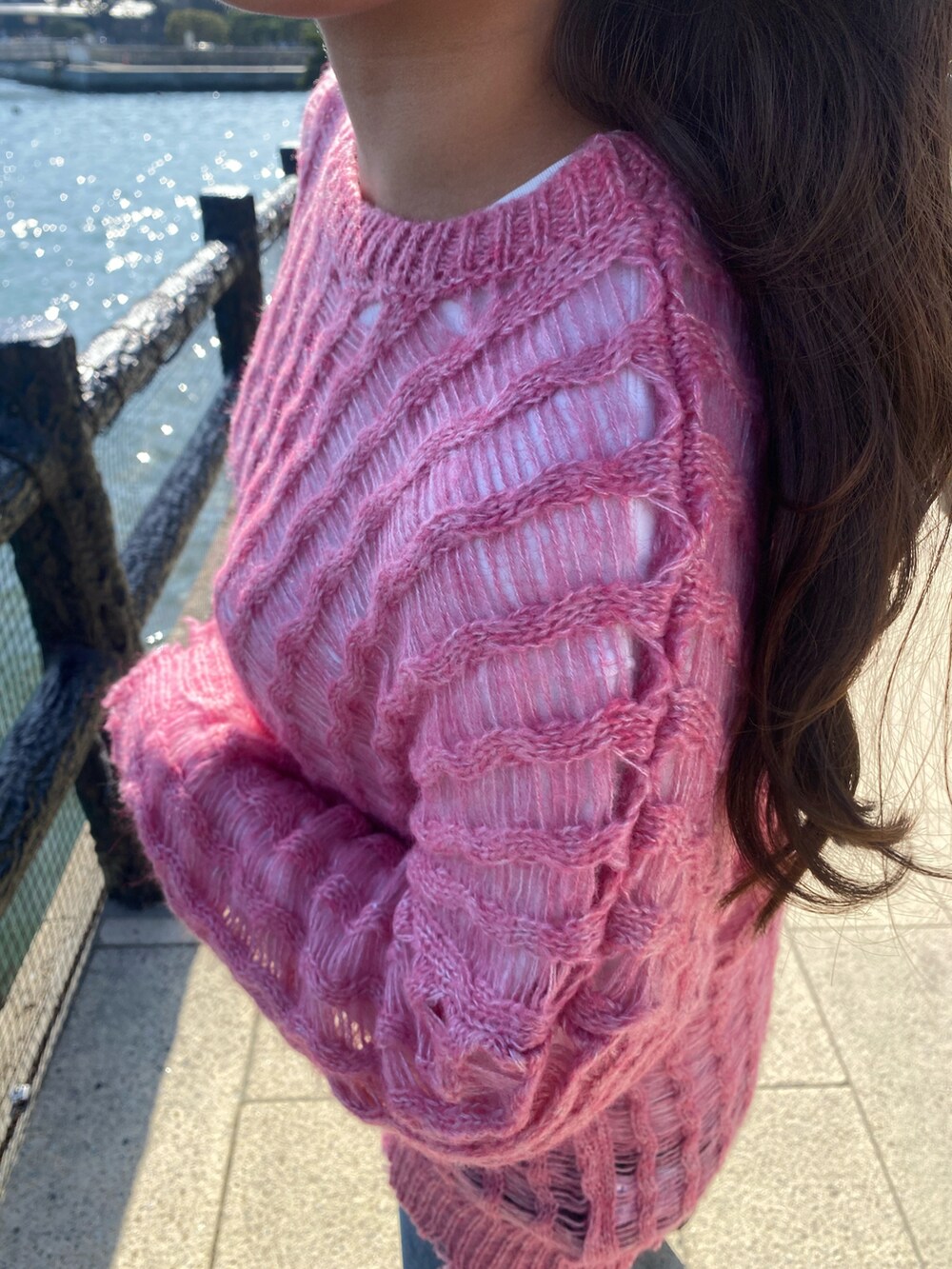 ピンク系のニット/セーター、ブルー系のデニムパンツ、ブラック系のスニーカーを着用したレディースの春コーディネートの2枚目の写真