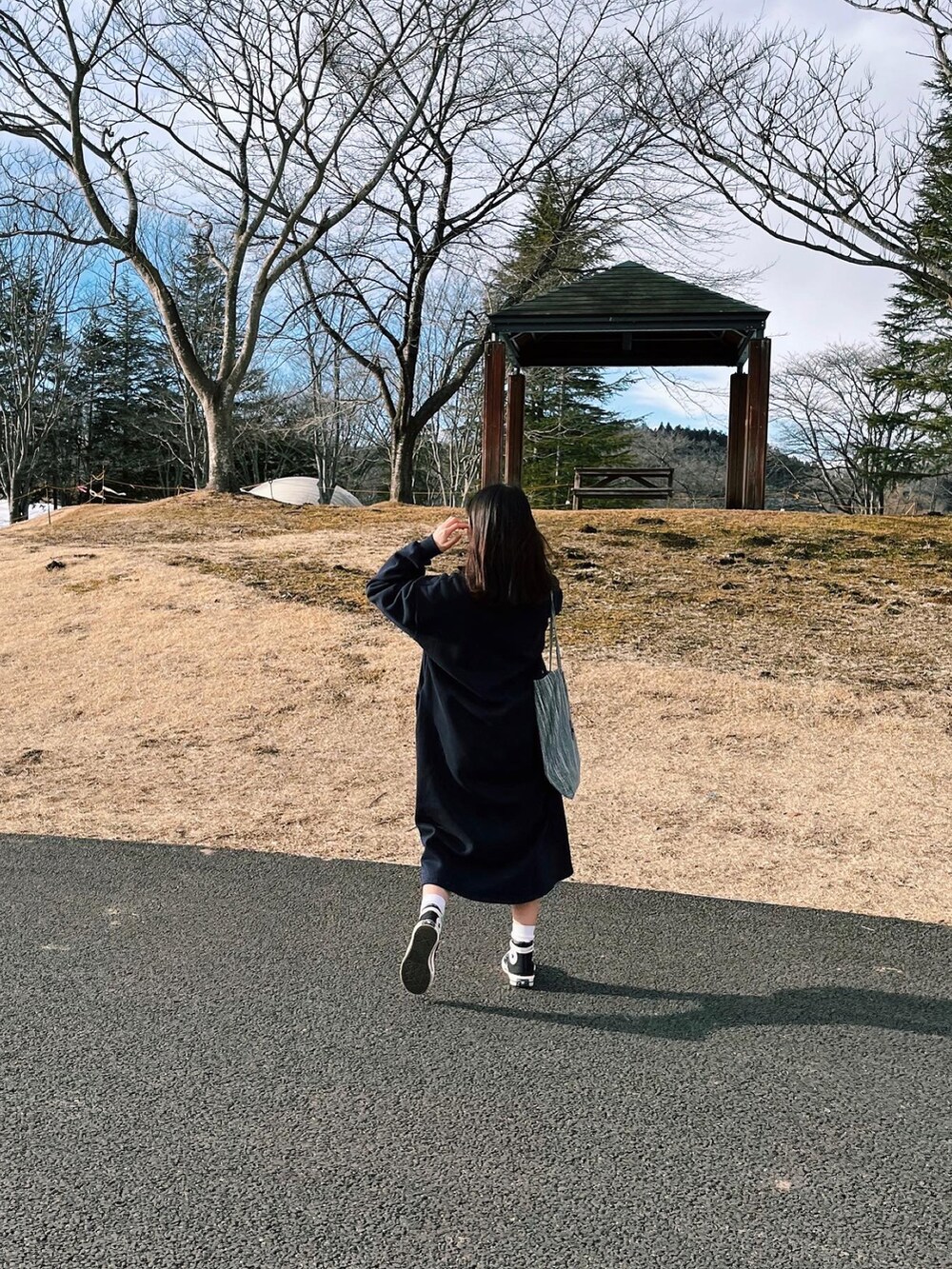 ブルー系のワンピース、ブラック系のスニーカー、オレンジ系のニット/セーターを着用したレディースの春コーディネートの2枚目の写真
