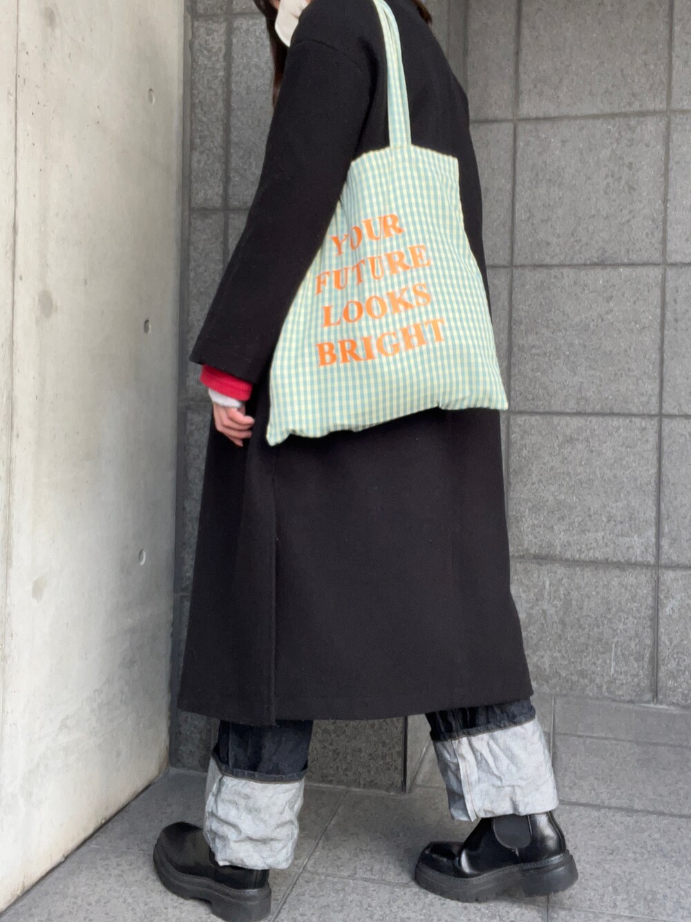 ブラック系のノーカラーコート、レッド系のカーディガン/ボレロ、グレー系のトップスを着用したレディースの冬コーディネートの3枚目の写真