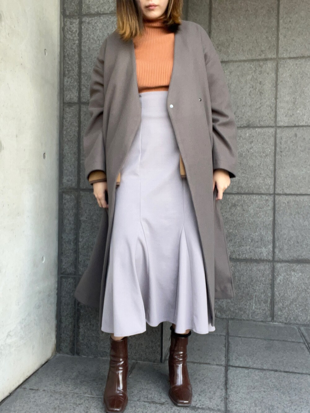 ブラウン系のジャケット/アウター、オレンジ系のニット/セーター、ブルー系のスカートを着用したレディースの冬コーディネートの2枚目の写真