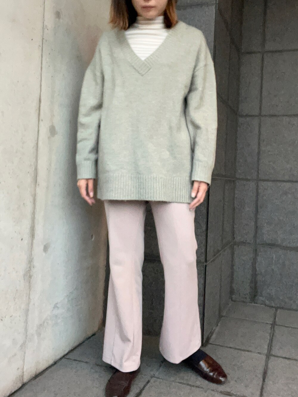 グリーン系のニット/セーター、ブラック系のノーカラーコート、ホワイト系のTシャツ/カットソーを着用したレディースの冬コーディネートの2枚目の写真